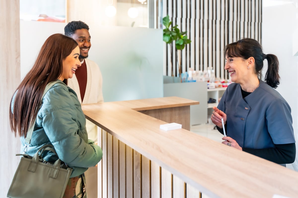 Happy patient greeted at the front desk of a dental clinic