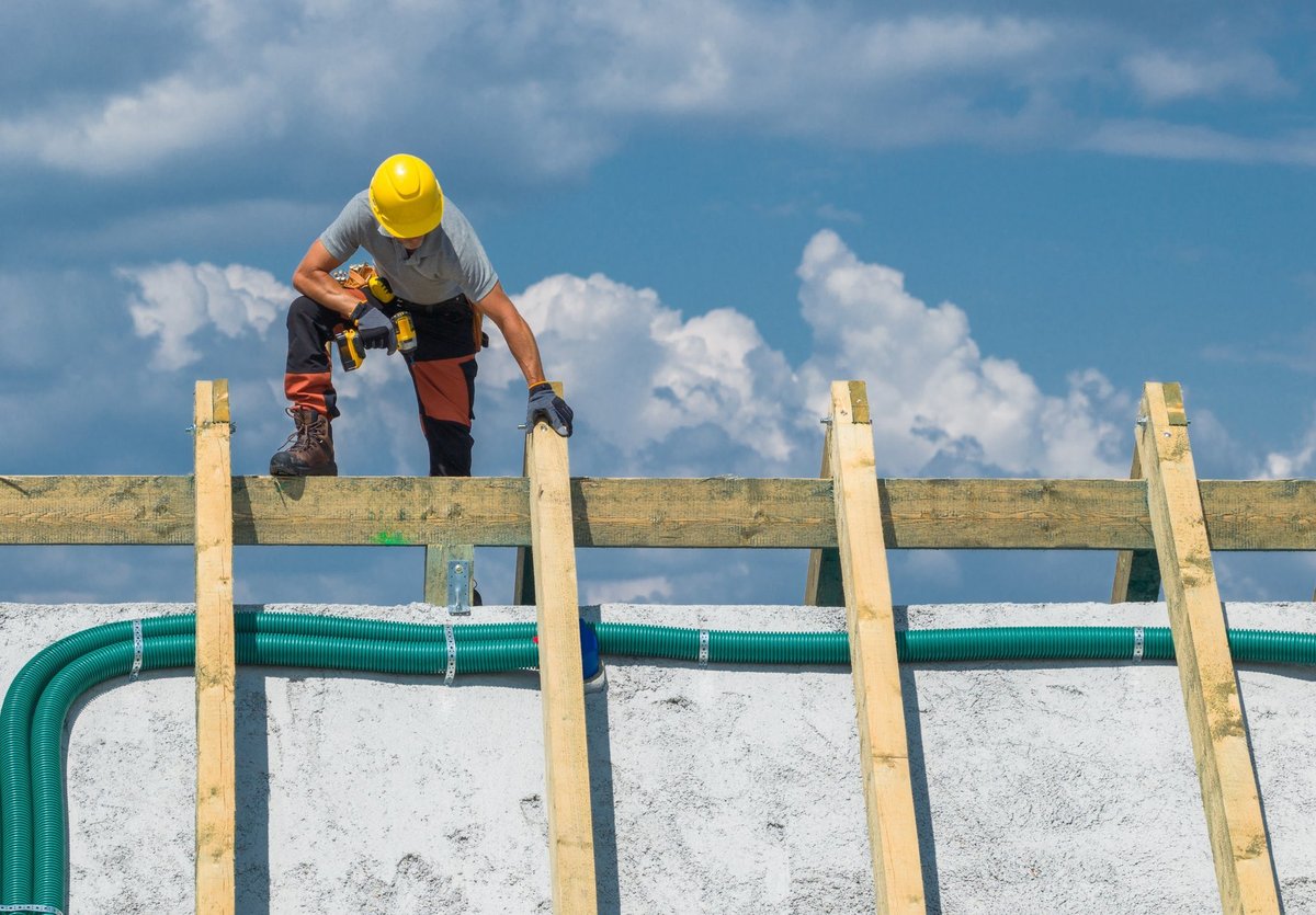 A roofing worker carefully placing wooden beams on a roof structure, representing skilled service trades delivering real results