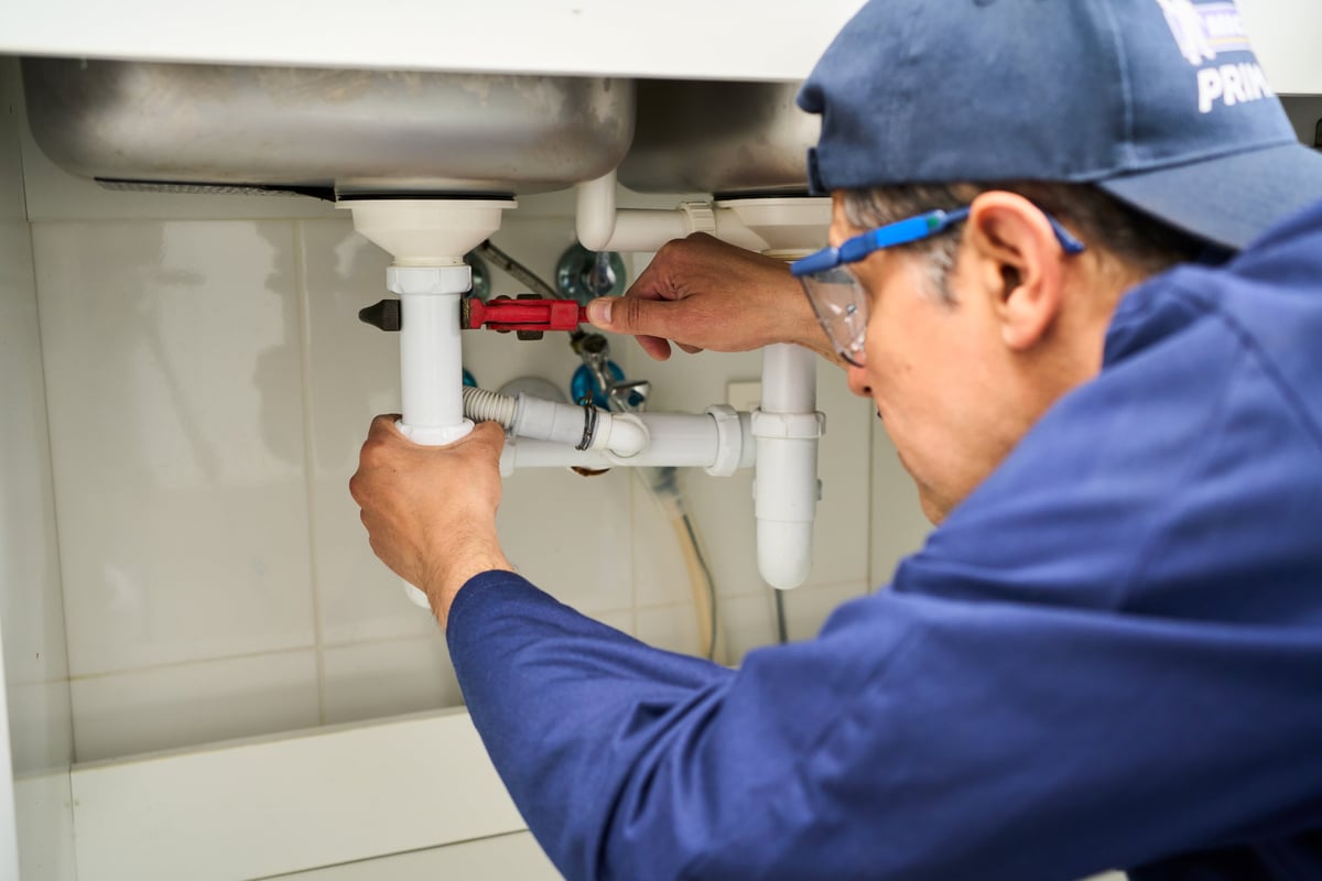 Plumber repairing sink pipes during a residential maintenance call